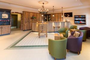 a lobby with a bar with green chairs and tables at Klosterbräu Schlehdorf in Schlehdorf