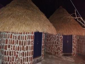 2 cabañas con techo de paja por la noche en Dragonfly Hostel and Homestay, en Nusa Penida