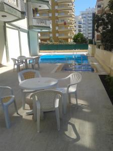 un patio con mesas y sillas junto a una piscina en Aygun Apartment 2 en Mahmutlar