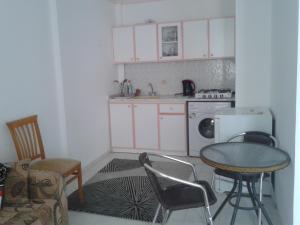 a kitchen with white cabinets and a table and chairs at Aygun Apartment 2 in Mahmutlar