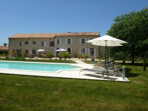 a pool with an umbrella and two chairs and a table at Domaine du Papillon in Lesparre-Médoc