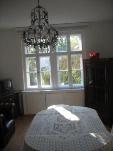 a room with a chandelier and a table in front of windows at Ferienwohnung Westend-Grunewald in Berlin