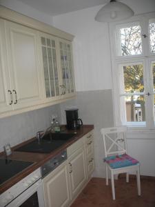 a kitchen with white cabinets and a sink and a chair at Ferienwohnung Westend-Grunewald in Berlin