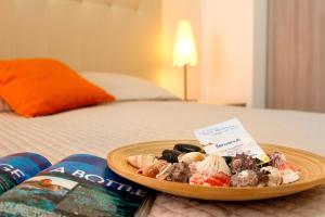 einen Teller mit Essen auf einem Bett mit einem Buch in der Unterkunft Residence Teclini in Castiglione della Pescaia