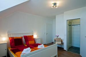 Schlafzimmer mit einem Bett mit roten und orangefarbenen Kissen in der Unterkunft Bed & Breakfast BonnaNotte in Essen