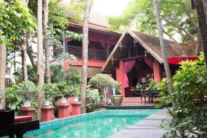 a resort with a swimming pool in front of a building at Tri Yaan Na Ros Colonial House in Chiang Mai