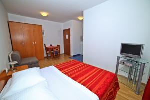 a hotel room with a bed and a television at Apartments Bozikovic in Podstrana