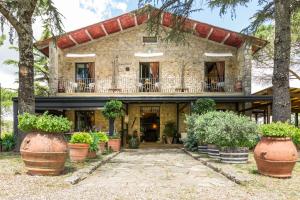 una vecchia casa in pietra con piante in vaso davanti di Villa Di Capovento a Castellina in Chianti