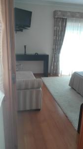 a bedroom with a bed and a couch and a television at Quarto/Suite de Charme in Viana do Castelo