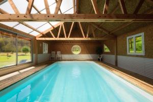 - une grande piscine dans une maison avec une grande fenêtre dans l'établissement Le Moulin Berthon, à Vernusse