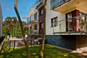 a building with balconies and a yard with a tree at Villa Aqua BlueApart Jurata in Jurata