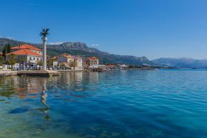a body of water with a town and a palm tree at Apartman Ita in Kaštela