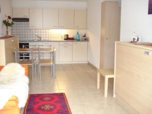 cocina con armarios blancos, mesa y sillas en Ferienwohnung Lenggenhager Plantzette en Sierre