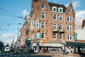 een groot bakstenen gebouw op de hoek van een straat bij Princess Hostel Leidse Square Amsterdam in Amsterdam