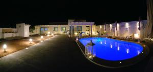 una piscina azul frente a una casa por la noche en Residence Nonna Mariuccia en Mazara del Vallo