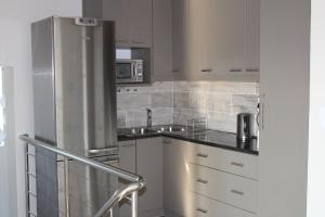 a kitchen with a stainless steel refrigerator and white cabinets at Island Style in Velddrif