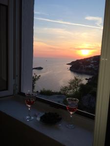 zwei Gläser Wein auf einer Fensterscheibe mit Sonnenuntergang in der Unterkunft Guesthouse Maritimo in Ulcinj