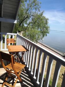 a wooden table and chairs on a porch overlooking the water at Namelis prie marių in Nida