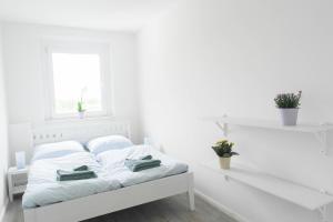 ペーネミュンデにあるSunny Apartmentの白いベッドルーム(タオル付きのベッド付)