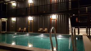 a swimming pool in a building with tables and chairs at Na-tub Hostel in Ban Tai