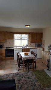 a kitchen with a table and some chairs and a table and a kitchen with at Fairgreen Cottages in Dungloe
