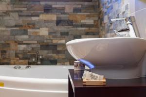 ein Badezimmer mit einem weißen Waschbecken und einer Badewanne in der Unterkunft El Molí de Pontons suites con jacuzzi spa in Pontons + 37 Fotos