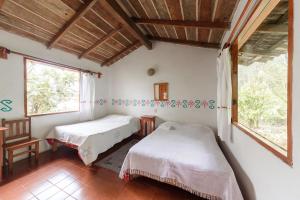 two beds in a room with two windows at Hotel Taselotzin in Cuetzalán del Progreso