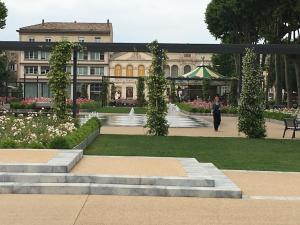 a woman walking in front of a building with a fountain at Appartements "Le 102" in Carcassonne