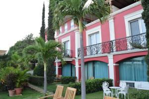 un bâtiment rose avec des chaises et des palmiers devant lui dans l'établissement Altos de Fontana, à Managua