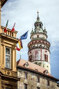 a clock tower with a flag on top of it at Hotel Dvorak Cesky Krumlov in Český Krumlov