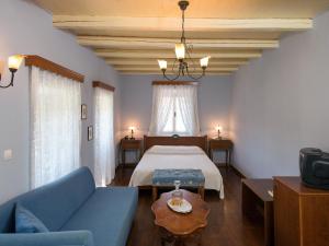 a bedroom with a bed and a blue couch at Villa De Loulia in Peroulades