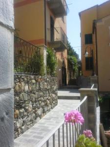 a building with a stone wall and pink flowers on a fence at Sole Terra Mare in Corniglia