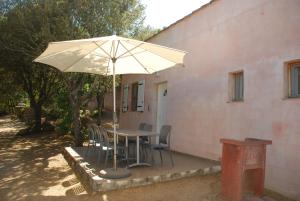 a table with chairs and an umbrella next to a building at Residence Ribellinu in Pianottoli-Caldarello