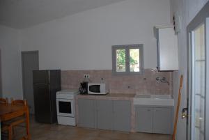a kitchen with a microwave and a sink and a refrigerator at Residence Ribellinu in Pianottoli-Caldarello