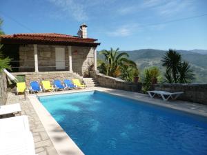 a swimming pool with chairs and a house at Casas das Guimbras in Geres
