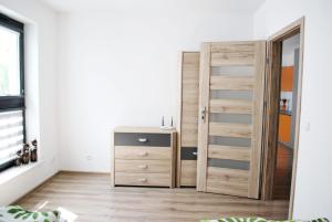 a bedroom with a wooden door and a dresser at Apart Morze apartamenty Vento in Władysławowo