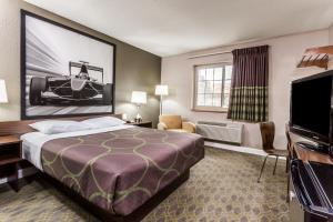 a hotel room with a bed and a flat screen tv at Super 8 by Wyndham Willows in Willows