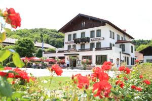 ein weißes Gebäude mit roten Blumen davor in der Unterkunft Gasthof Prinzregent Superior in Marquartstein