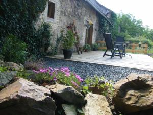 a patio with a table and chairs and flowers at Pear Tree Gite in Génis