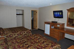 a hotel room with a bed and a desk and a television at South Bay Motel in Copiague