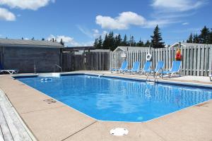 a swimming pool with blue chairs and a fence at Hidden Acres Cottages in Cavendish