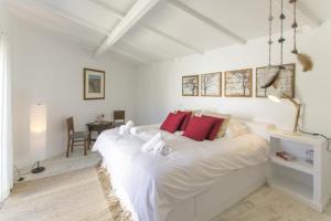 a white bedroom with a large white bed with red pillows at O Moinho da Roca in Azoia