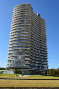 a tall apartment building with a grass field in front of it at Alexander Boulevard - Apartamento en Piso alto in Punta del Este