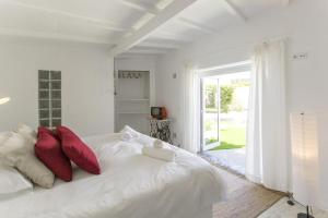 a white bedroom with a white bed with red pillows at O Moinho da Roca in Azoia