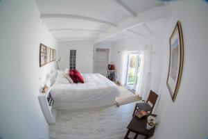 a white bedroom with a bed with red pillows at O Moinho da Roca in Azoia