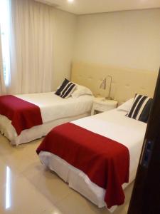 Habitación de hotel con 2 camas con sábanas rojas y blancas en Realty PY Saravi, en Asunción