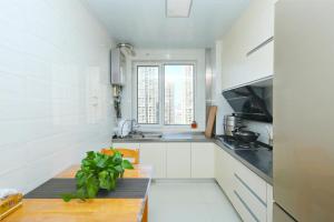 een witte keuken met een tafel en een raam bij 青岛金沙滩全家幸福三居室海景公寓Blessed Family Apartment in Qingdao