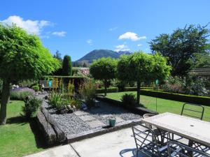 a garden with a table and chairs and trees at Marchmont Gardens in Hanmer Springs