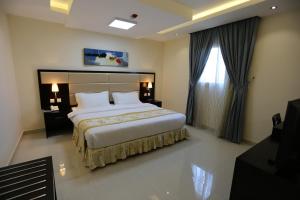 a bedroom with a large bed and a large window at Arjaan Altakhassusi Hotel Suites in Riyadh