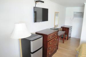 a room with a dresser and a tv and a lamp at Islander Motel in Ocean City